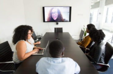 Employees gather in conference room for virtual events